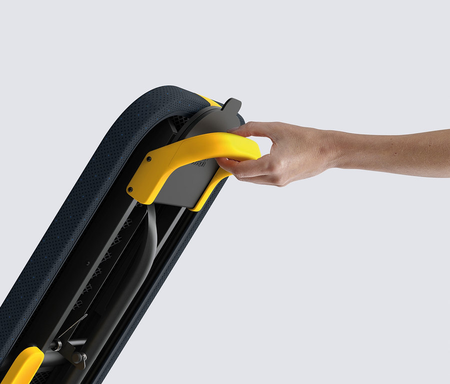 Eine Hand hält einen gelben Griff an einem schwarzen Rahmen mit blauer Polsterung.