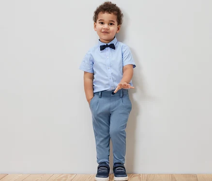 Junge mit blauem Hemd, Fliege und Kinder-Chinohose.