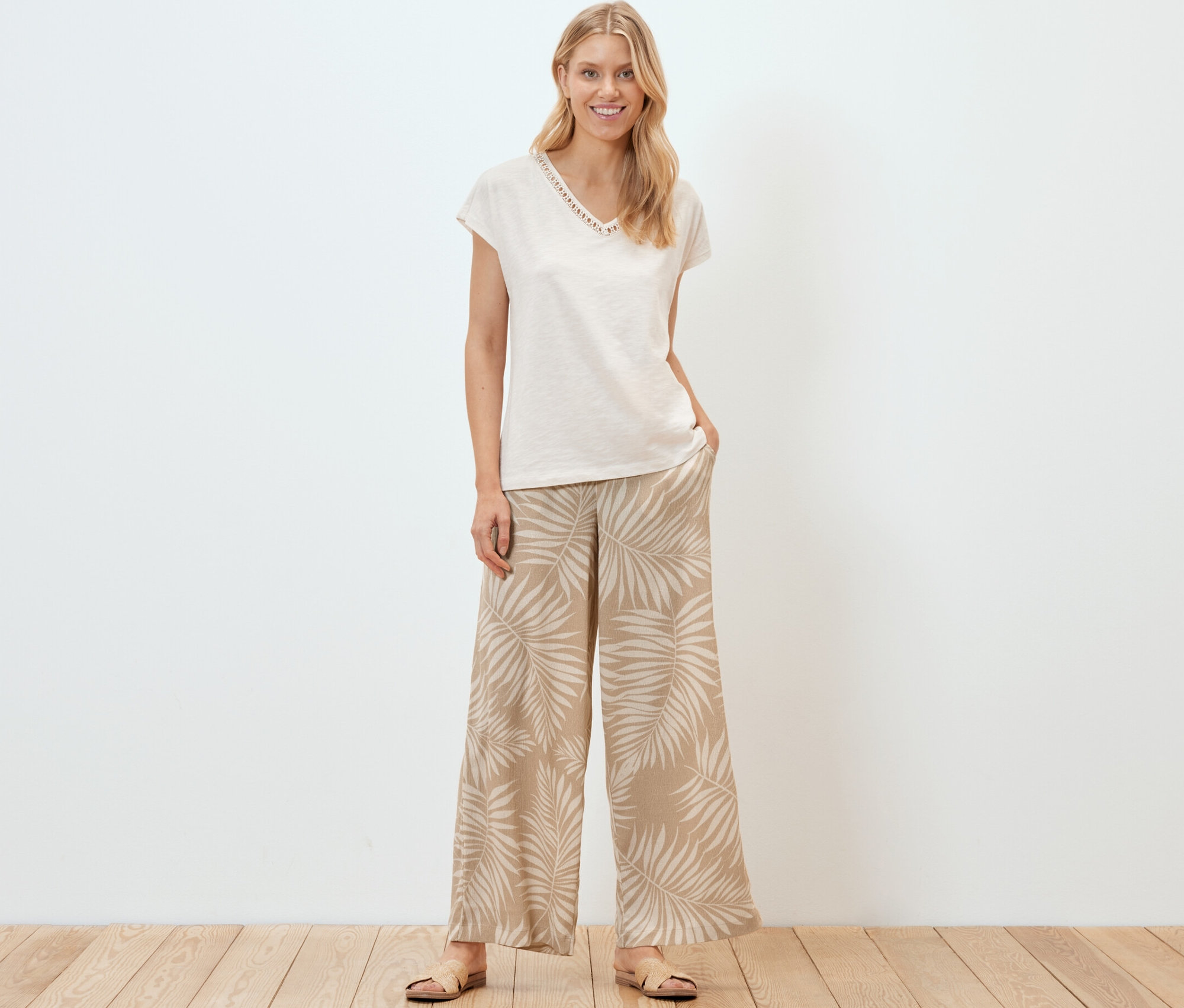 Frau steht und trägt eine strukturierte Palazzohose mit Alloverprint.