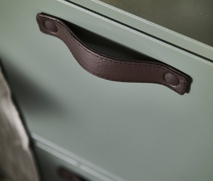 Detailaufnahme eines olivgrünen vtwonen Stage Schranks mit braunem Ledergriff.