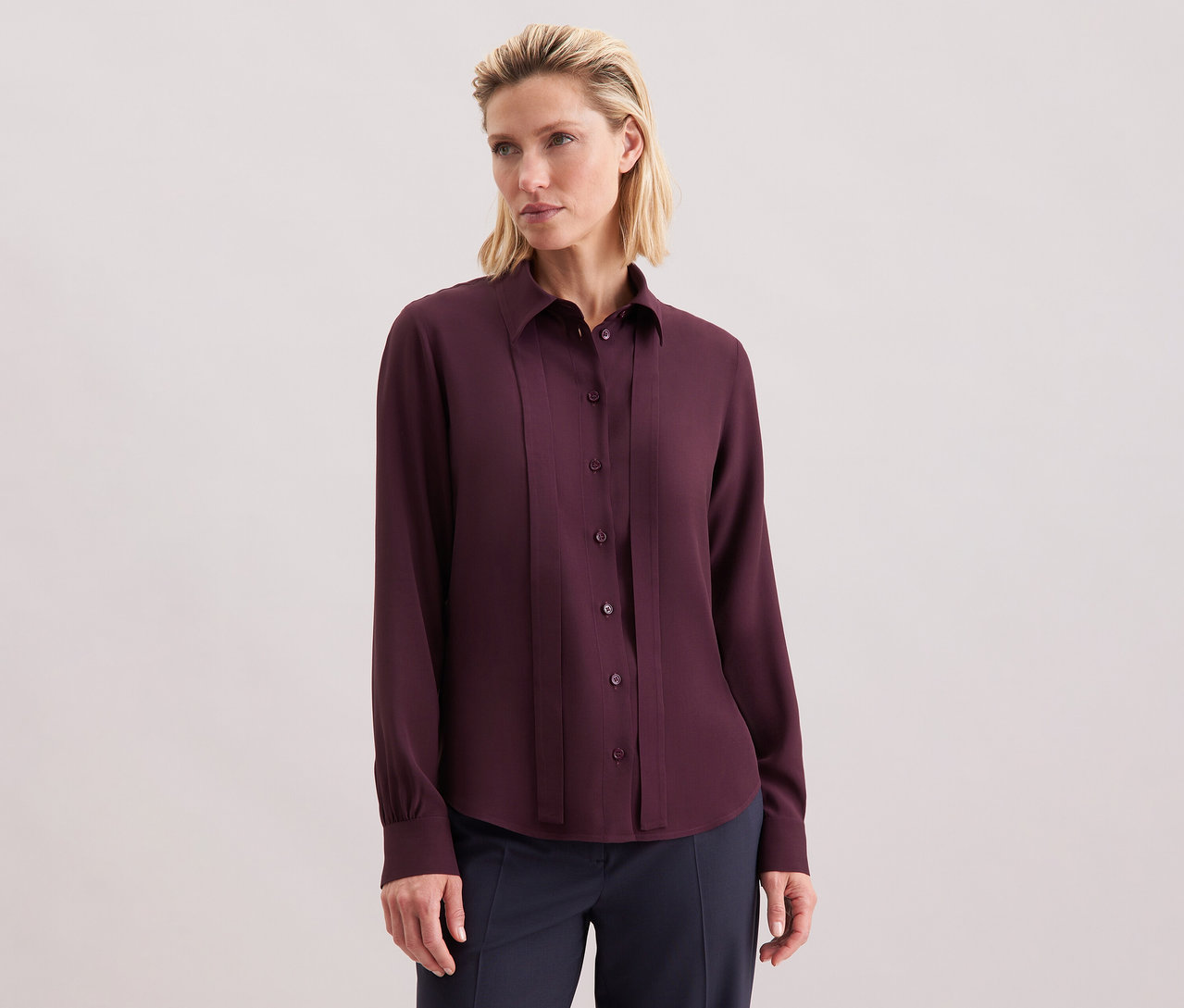 Frau trägt eine Seidensticker Schluppenbluse aus Viskose, bordeauxrot, mit Knöpfen.