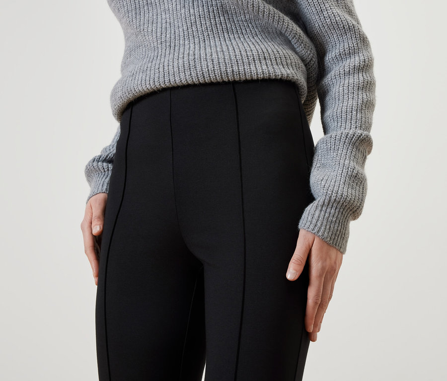 Detailaufnahme einer Frau mit schwarzer Hose und grauem Pullover.