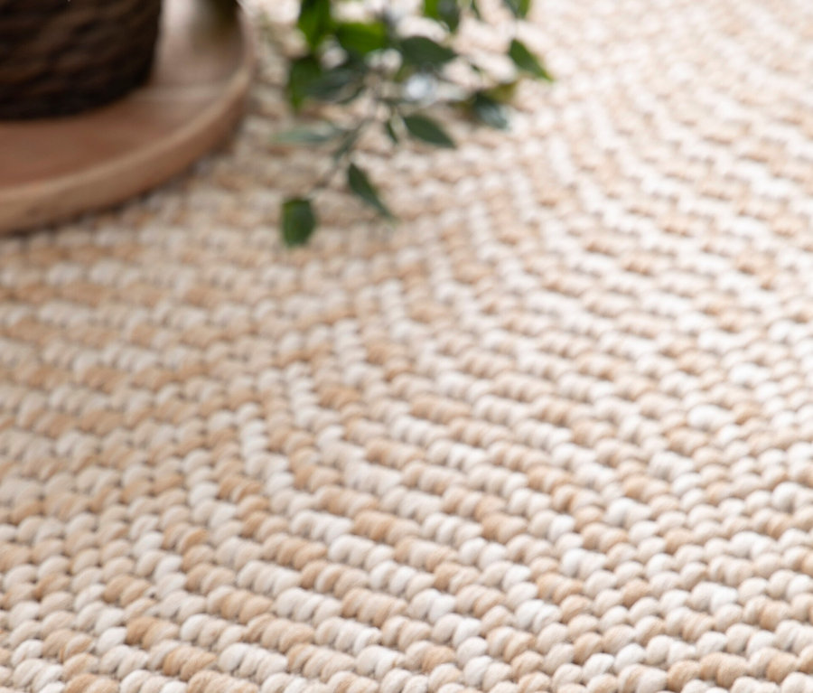 Nahaufnahme eines beigen Teppichs »Twine« im Fischgrätenmuster.