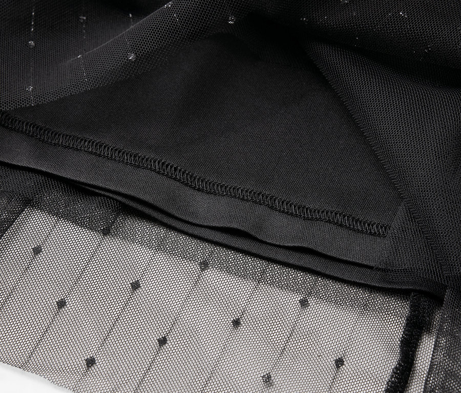 Detailaufnahme eines schwarzen Tüllkleidungsstücks mit Punktmuster und Innenfutter.
