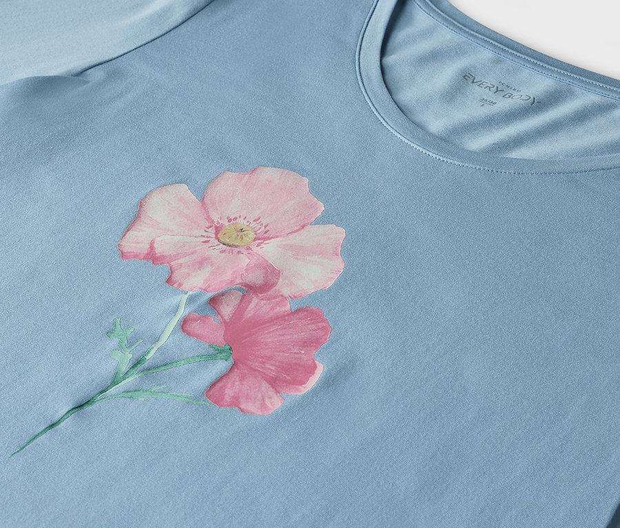 Detail eines hellblauen T-Shirts mit einem Aufdruck aus zwei rosa Blumen.