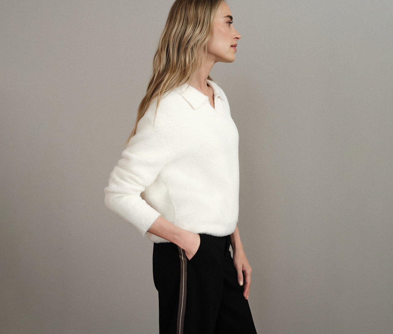 Frau im Profil trägt weißen Street One Strickpullover mit Polokragen und schwarze Hose.