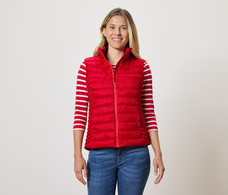 Frau trägt eine rote Steppweste, ein gestreiftes T-Shirt und Jeans.