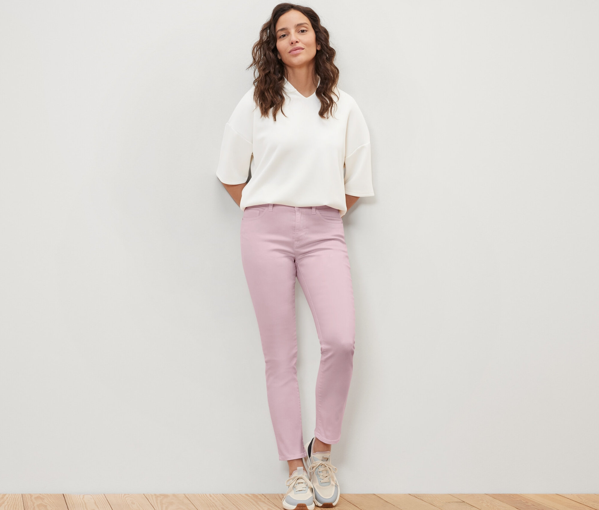 Eine Frau steht und trägt eine Colored Jeans ‒ Fit »Emma« und eine weiße Bluse.