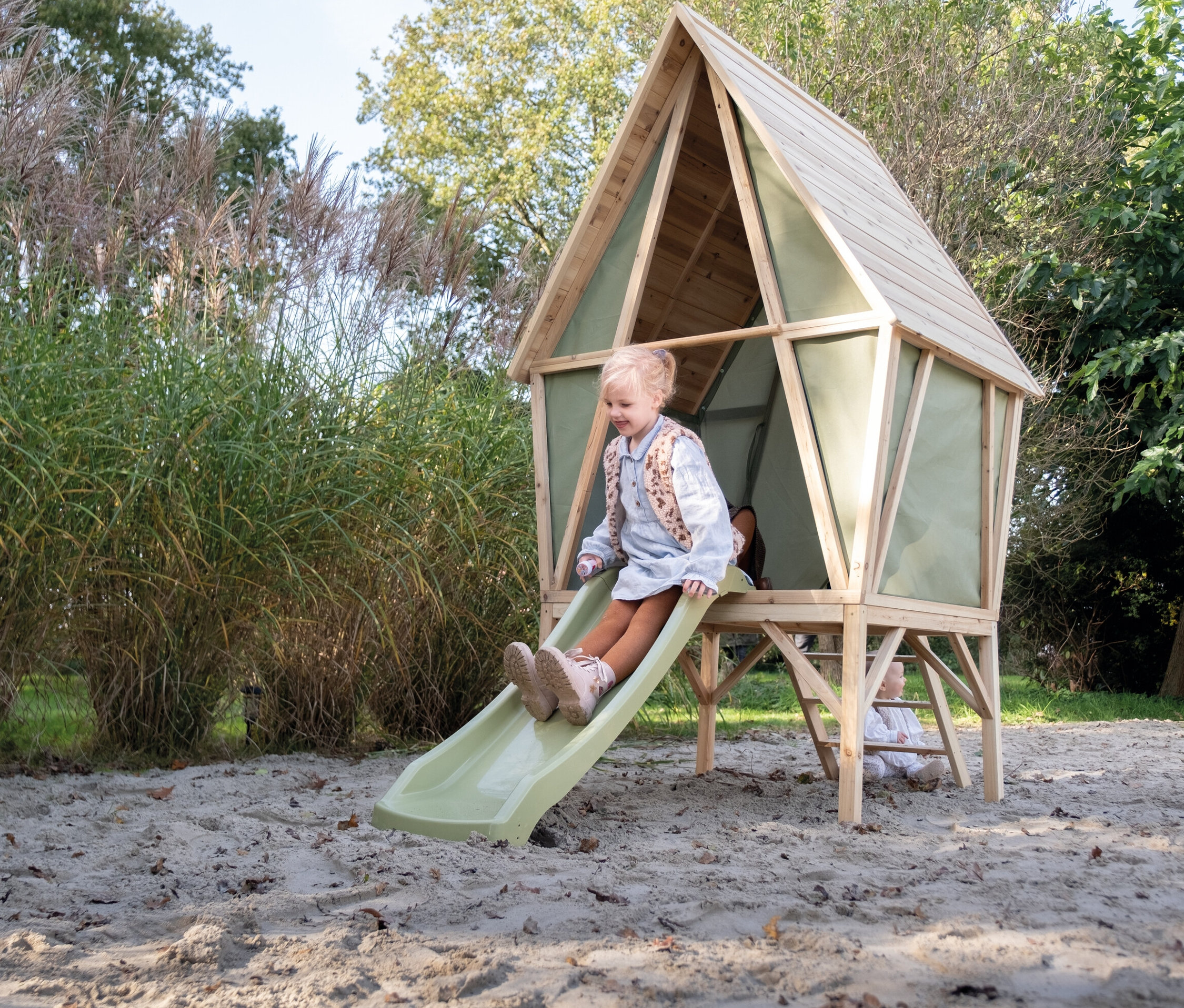 Mädchen rutscht die Rutsche vom EXIT Spielhaus »Yuki 300« hinunter.