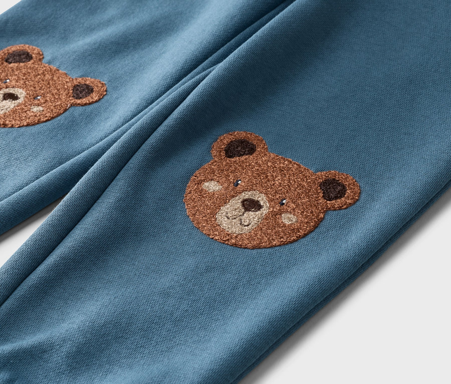 Nahaufnahme von blauen Hosen mit Teddybär-Applikationen auf beiden Beinen.