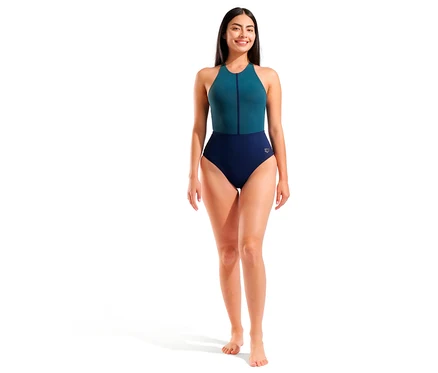Lächelnde Frau steht in einem arena Shapewear Damen-Badeanzug Silvia B-Cup Cross Back. Der einteilige Badeanzug ist oben türkis mit Reißverschluss und unten marineblau.