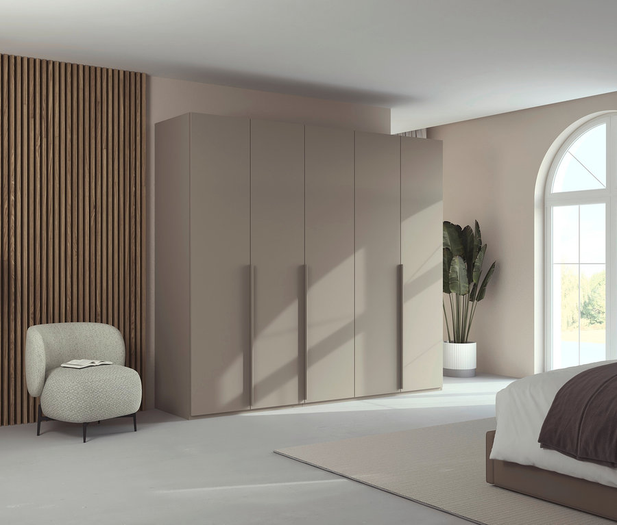 Schlafzimmer mit großem, beigem Kleiderschrank, Sessel mit Buch, Zimmerpflanze und Bogenfenster.