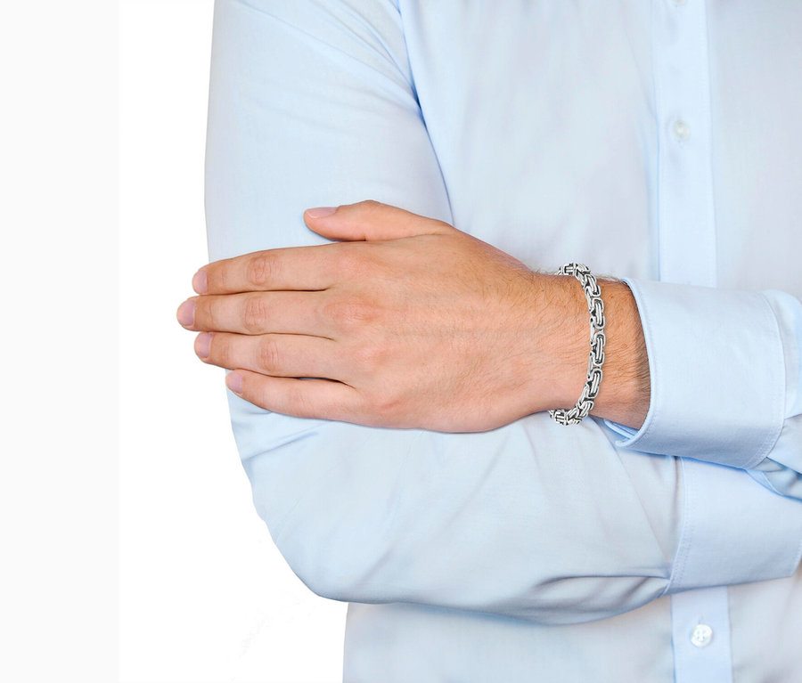 Mann mit verschränkten Armen, der ein silbernes Armband trägt.