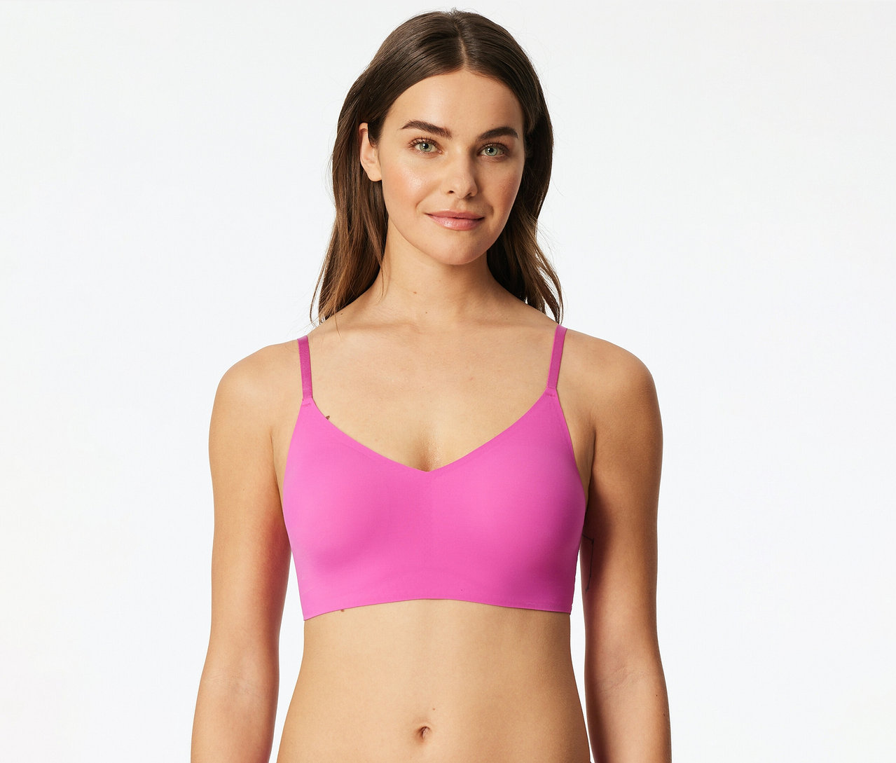 Eine Frau trägt ein pinkes SCHIESSER Invisible Bustier mit Pads und lächelt in die Kamera.