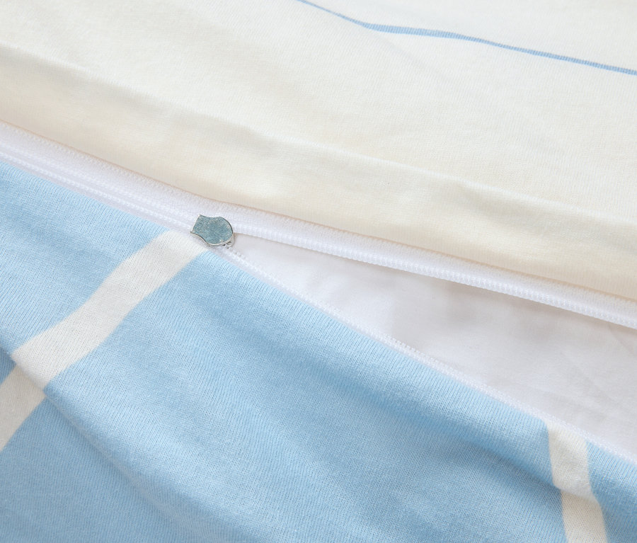 Detailansicht eines teilweise geöffneten Bettbezugs mit blau-weißem Karomuster und einem Reißverschluss.