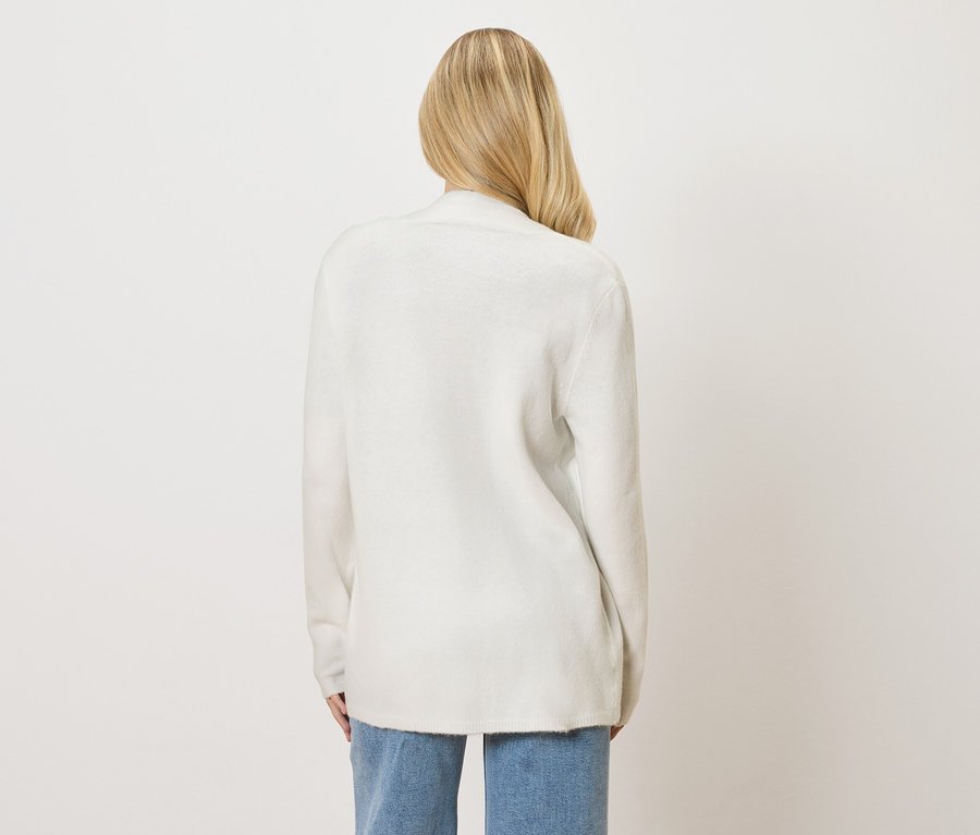 Rückansicht einer Frau mit blonden Haaren, die einen weißen Cardigan und Jeans trägt.