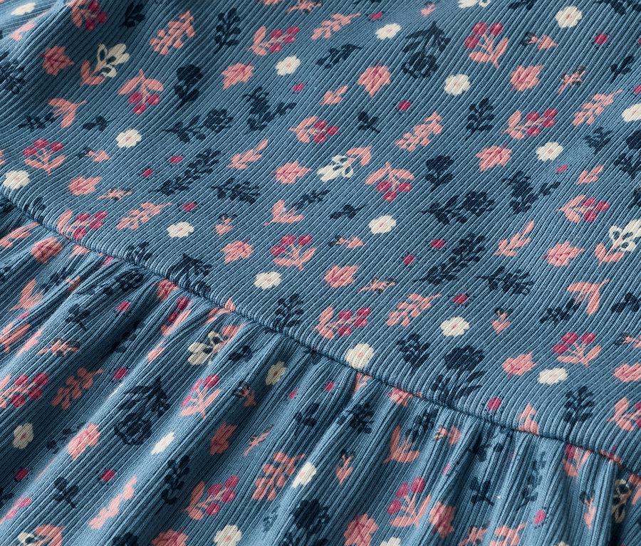 Nahaufnahme eines blauen Cordstoffes mit rosa, weißen und marineblauen Blumenmuster.