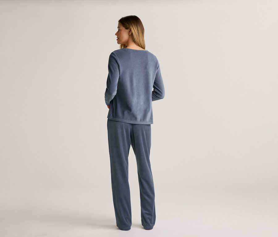 Eine Frau steht mit dem Rücken zur Kamera und trägt einen blauen Samtpyjama.