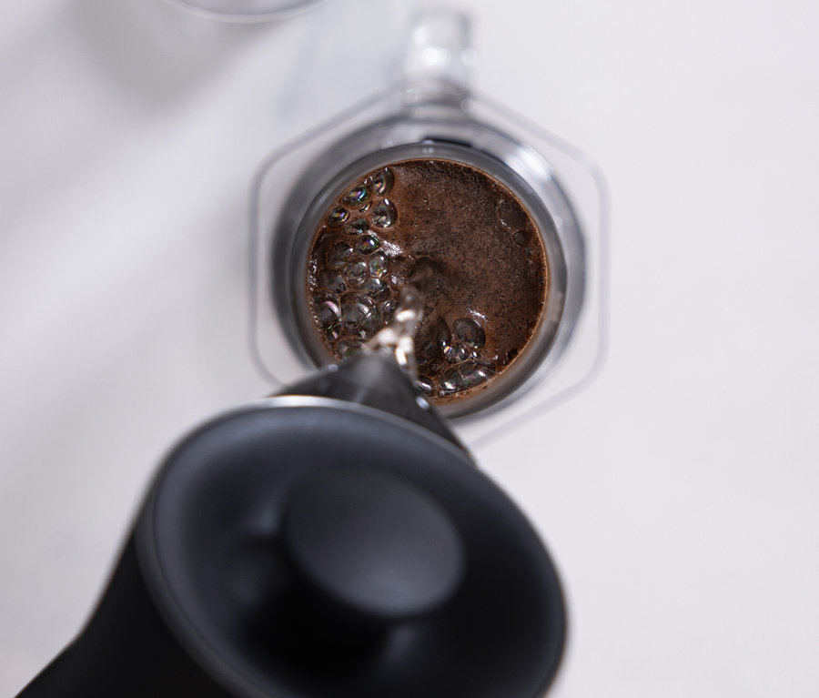 Wasser wird in einen transparenten AeroPress Coffee Maker »Clear« gegossen.