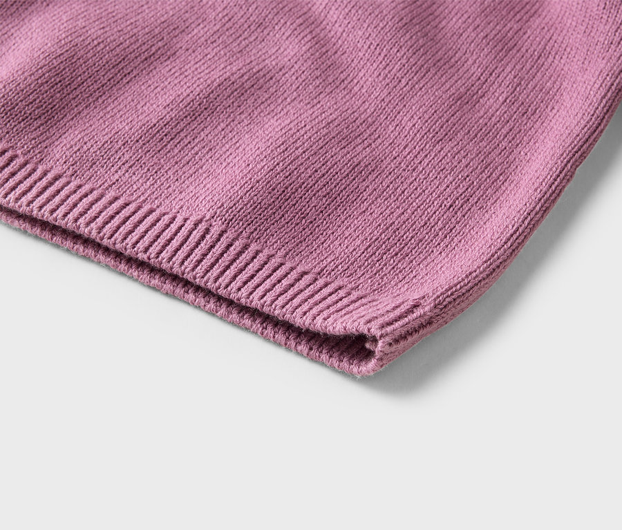 Nahaufnahme eines rosa Strickstoffs mit geripptem Saum, der die Textur der Maschen zeigt.