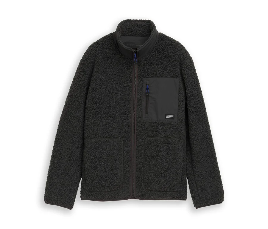 Dunkelgraue Tom Tailor Teddyjacke mit Stehkragen, durchgehendem Reißverschluss, zwei Seitentaschen und einer Brusttasche mit blauem Reißverschluss.
