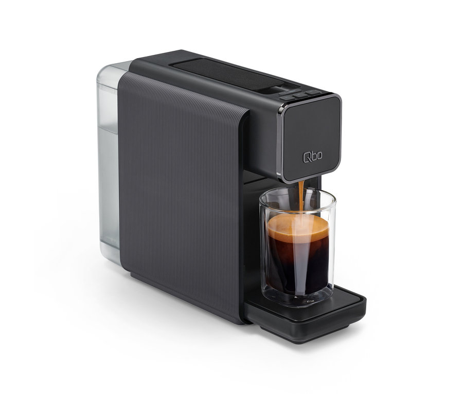 Dunkelgraue Qbo ONE Kapselmaschine, Soft Black, füllt Kaffee mit Crema in ein doppelwandiges Glas.
