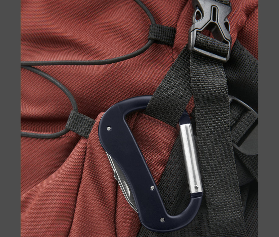 Nahaufnahme eines Karabinerhakens mit einem Multitool, befestigt an einem roten Rucksack.