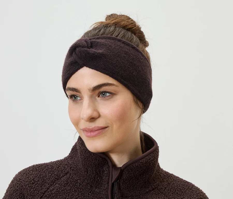 Frau mit braunem Stirnband und Fleecepullover. Das Stirnband ist vorne geknotet. Sie blickt nach links.