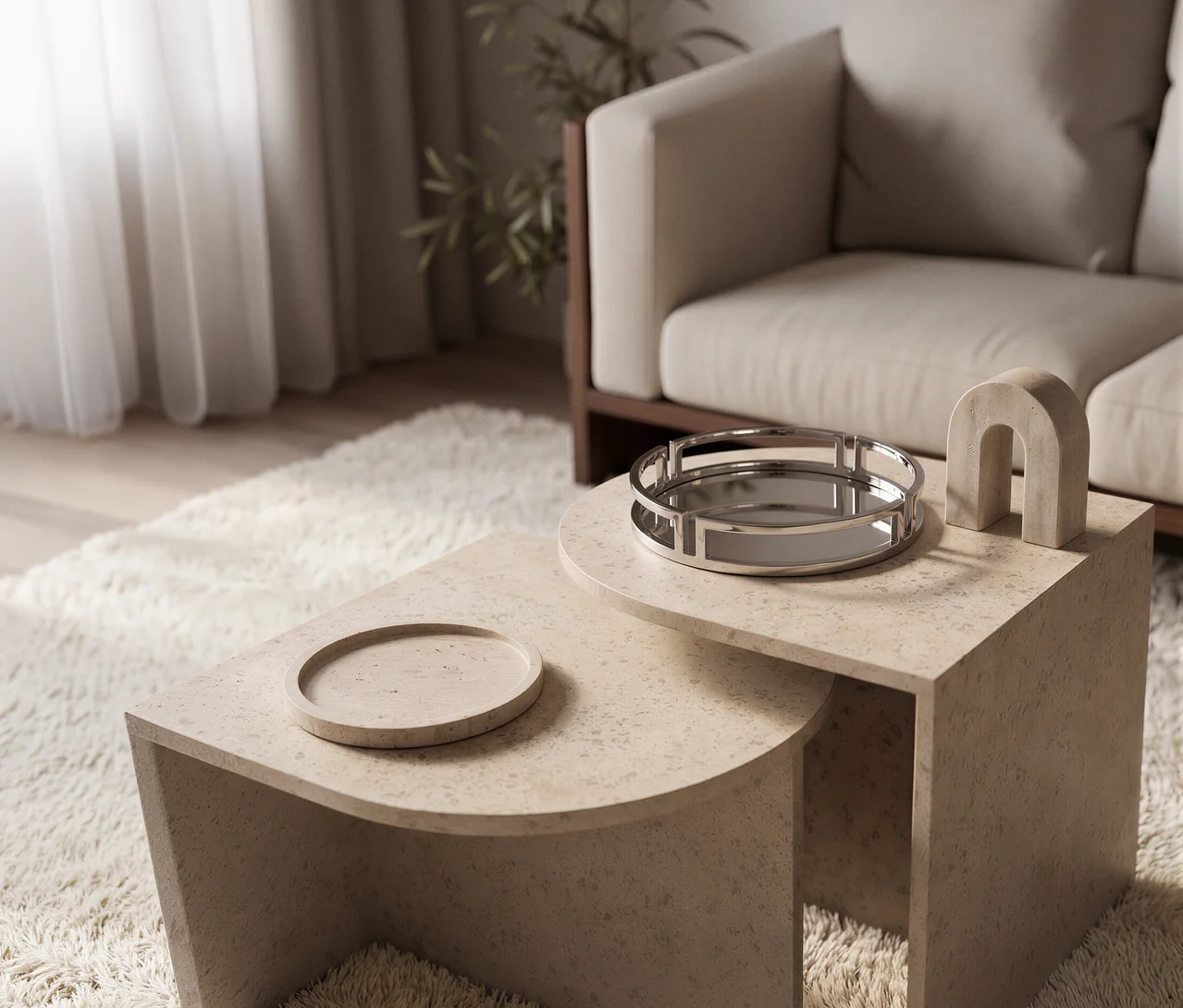 Zwei halbrunde Couchtische »Leo« stehen auf einem flauschigen Teppich. Der höhere Tisch trägt ein silbernes Spiegeltablett und einen Deko-Bogen, der niedrigere Tisch ein kleines rundes Tablett. Im Hintergrund ist ein cremefarbenes Sofa zu sehen.