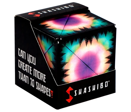 Schwarze Box mit einem Würfel, der ein farbenfrohes Polarlicht- und Baumsilhouetten-Design zeigt. Die Box trägt den Text 'SHASHIBO' und 'Kannst du mehr als 70 Formen erstellen?'