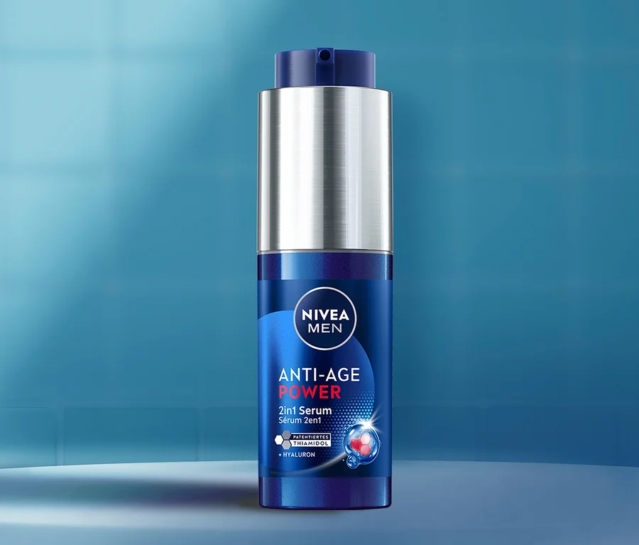Dunkelblaue Nivea Men Anti-Age Power 2in1 Serumflasche mit silbernem Pumpspender und blauem Verschluss. Das Etikett zeigt 'ANTI-AGE POWER', '2in1 Serum' und 'PATENTIERTES THIAMIDOL + HYALURON'.