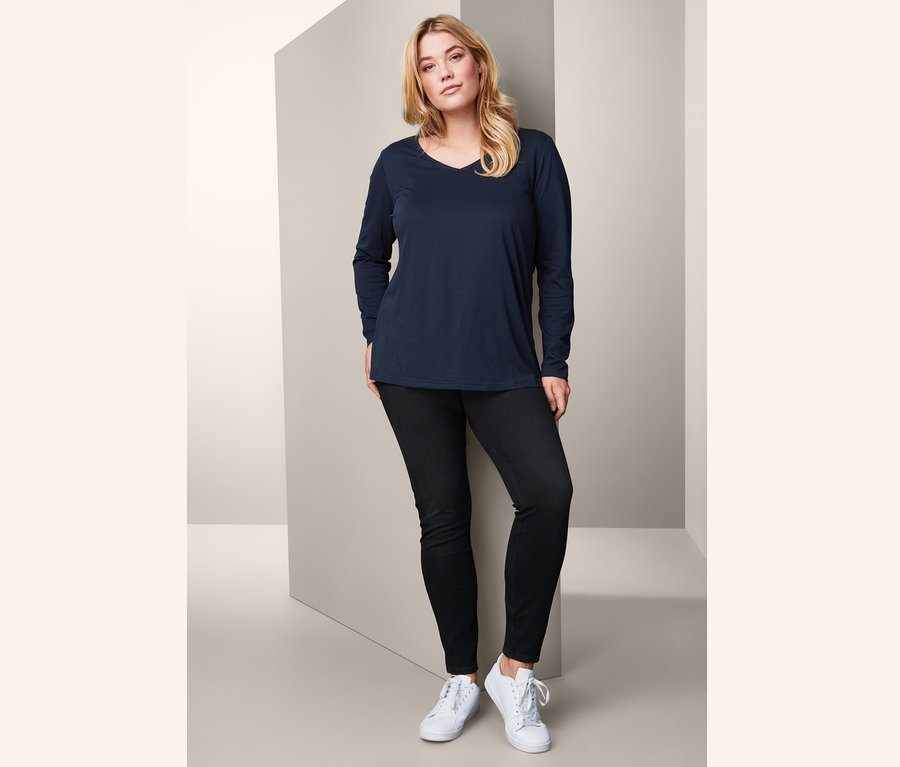 Frau posiert in Langarmshirt und Jeggings.