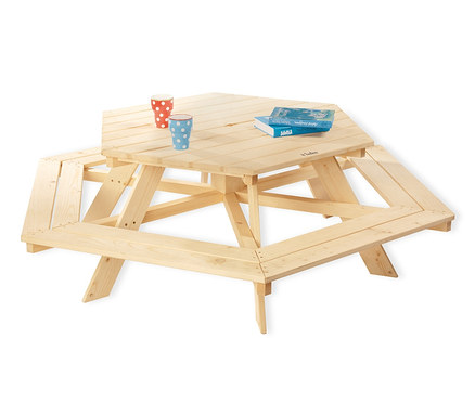 Zwei Becher und zwei Bücher auf einer sechseckigen Sitzgruppe »Nicki 6-Eck« von Pinolino aus Naturholz mit Sitzgelegenheiten.