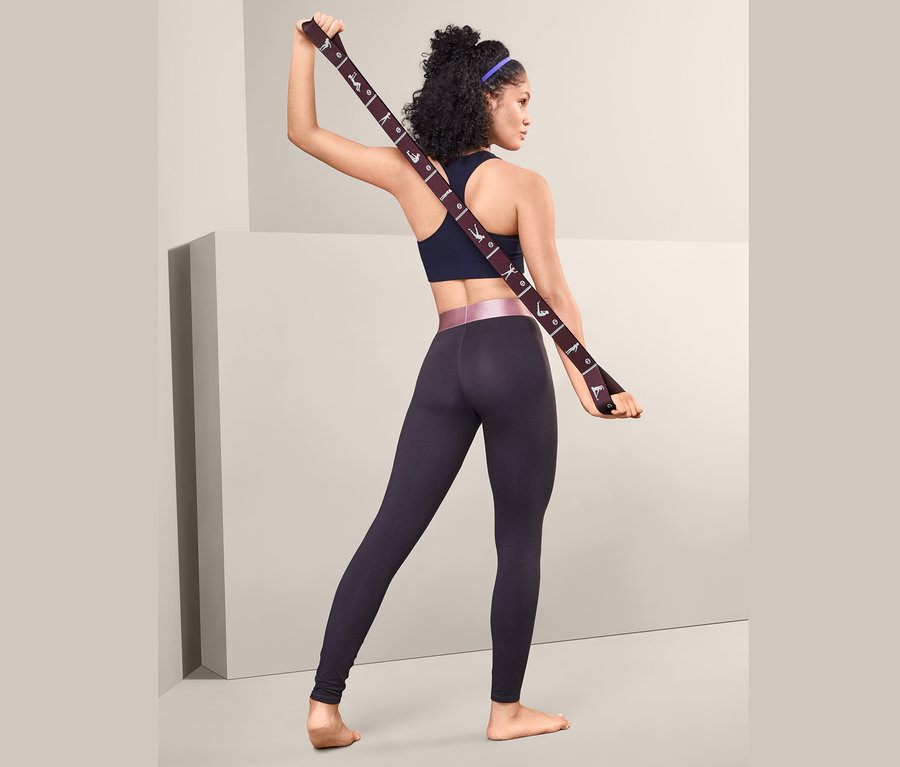Frau hält Fitness-Elastikband hinter ihrem Rücken.