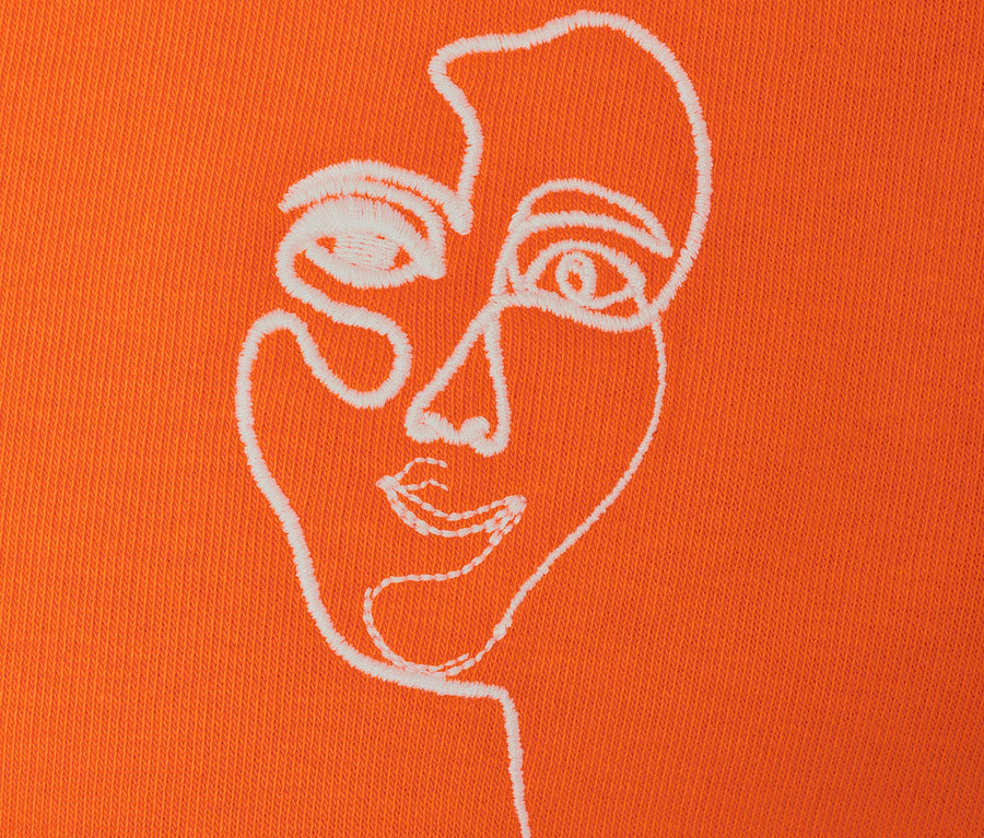 Detail eines orangefarbenen Sweatshirts mit Gesicht-Stickerei.