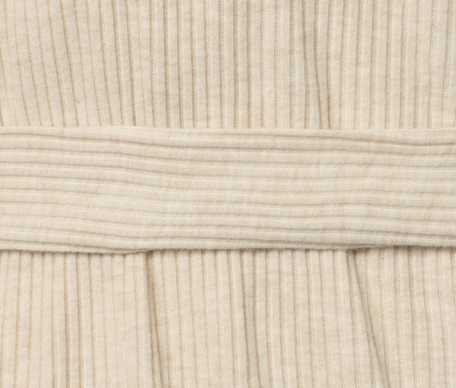 Detailaufnahme eines cremefarbenen Yoga-Wickel-Cardigans mit Rippenstruktur.