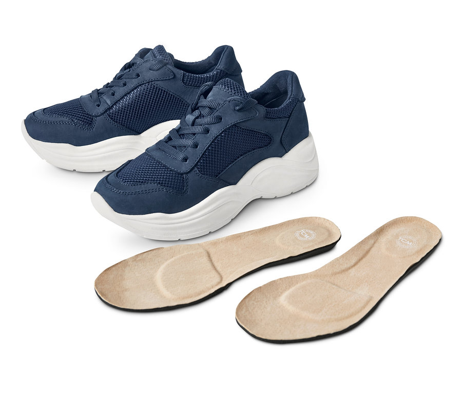 Zwei Leder-Sneaker und zwei Einlegesohlen liegen auf einem weißen Hintergrund.