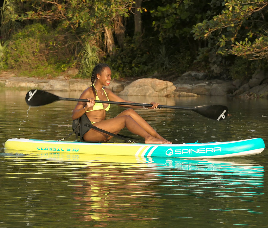 Frau sitzt auf einem Spinera SUP-Sitz und hält ein Paddel.