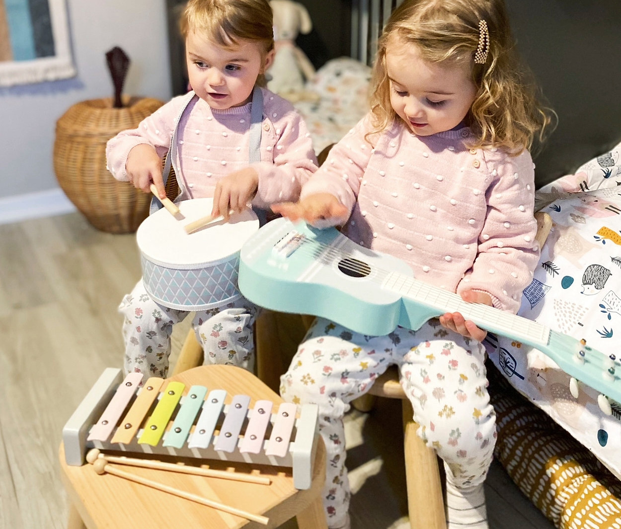 Zwei kleine Mädchen sitzen auf Stühlen und spielen mit einem small foot Musik-Set »Pastell«.