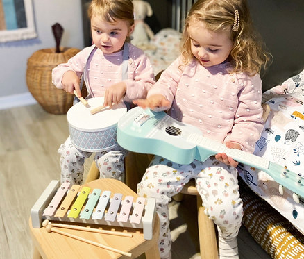 Zwei kleine Mädchen sitzen auf Stühlen und spielen mit einem small foot Musik-Set »Pastell«.