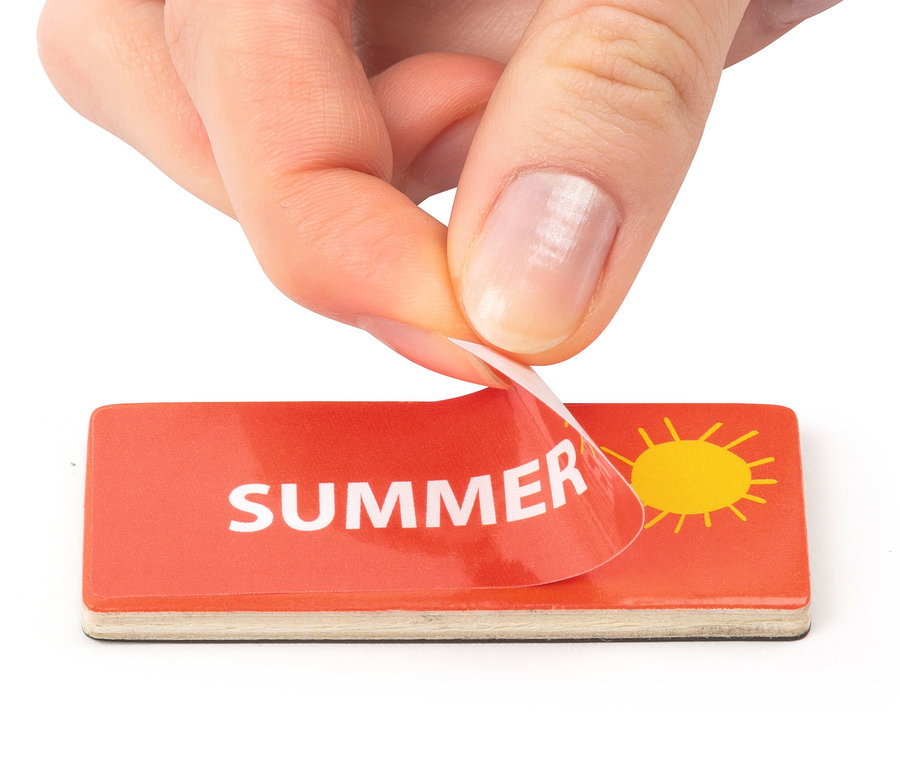 Eine Hand entfernt die Schutzfolie von einem Magneten mit der Aufschrift "SUMMER" und einer Abbildung der Sonne. small foot Wochenplaner »Educate«, magnetisch