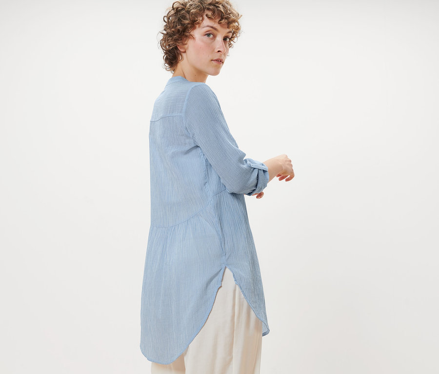 Frau posiert in gestreifter Longbluse.