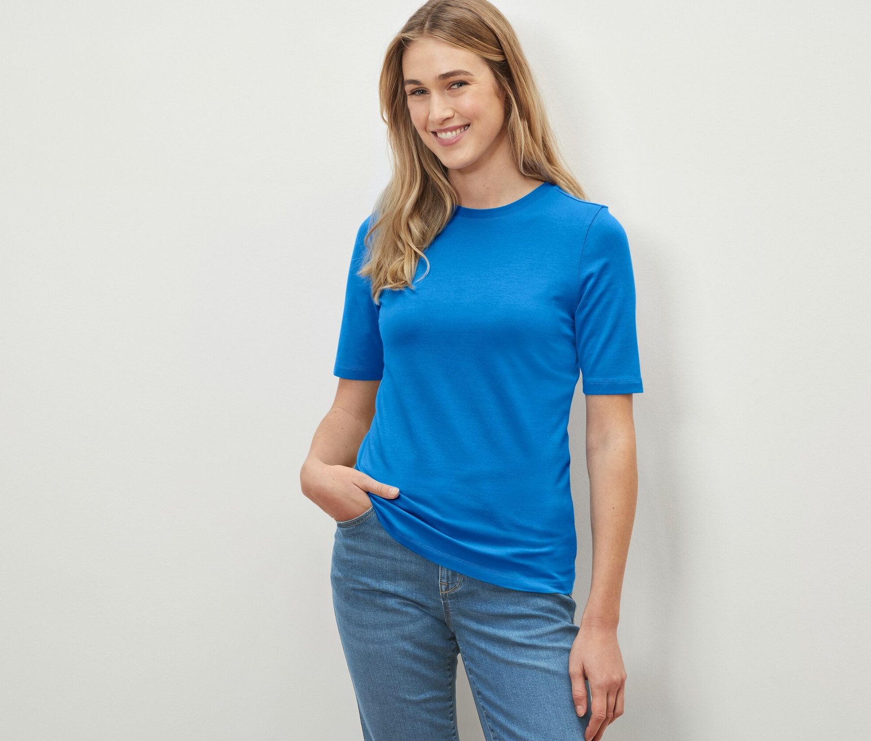 Frau posiert in einem kobaltblauen Halbarmshirt.