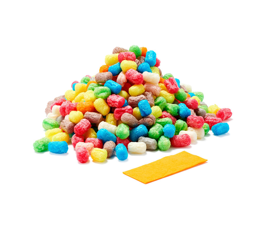 Ein Haufen bunter PlayMais®-Stückchen und ein gelber Schwamm.