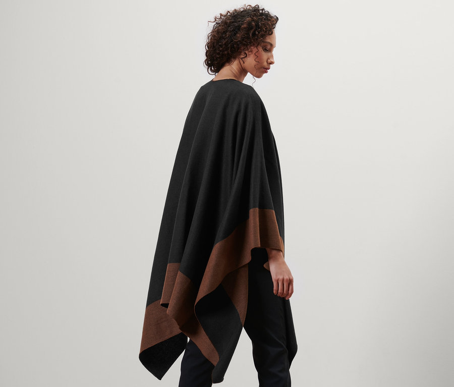 Frau trägt einen Wende-Poncho in Schwarz und Braun.