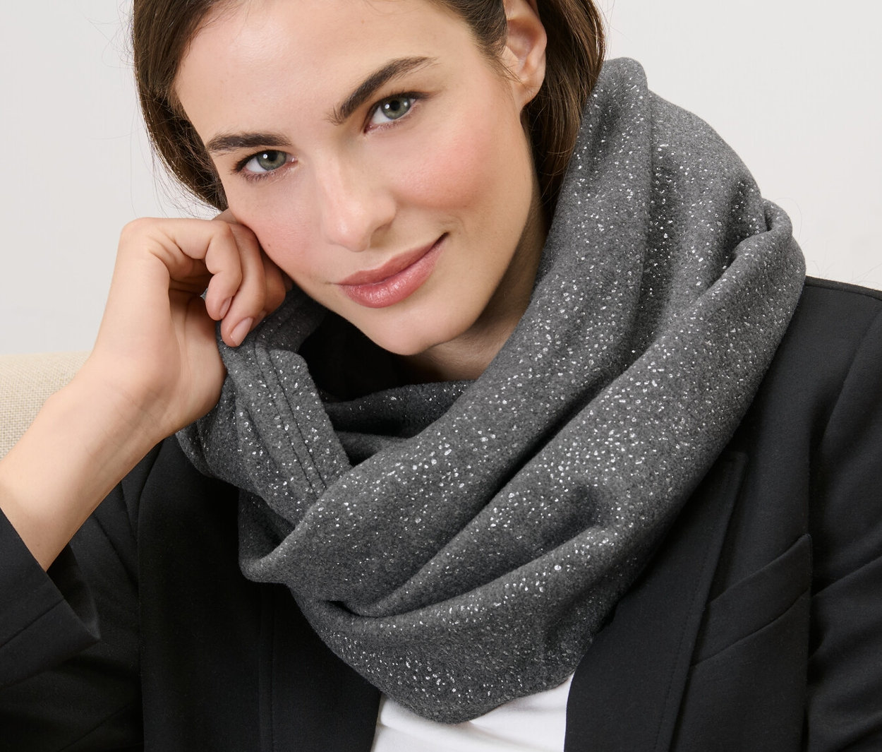 Frau sitzt mit einem glitzernden Fleece-Loop um den Hals.