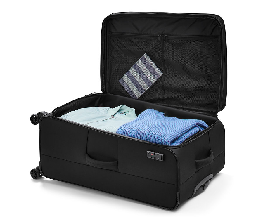 Offener Textilkoffer, groß, mit Kleidung darin.