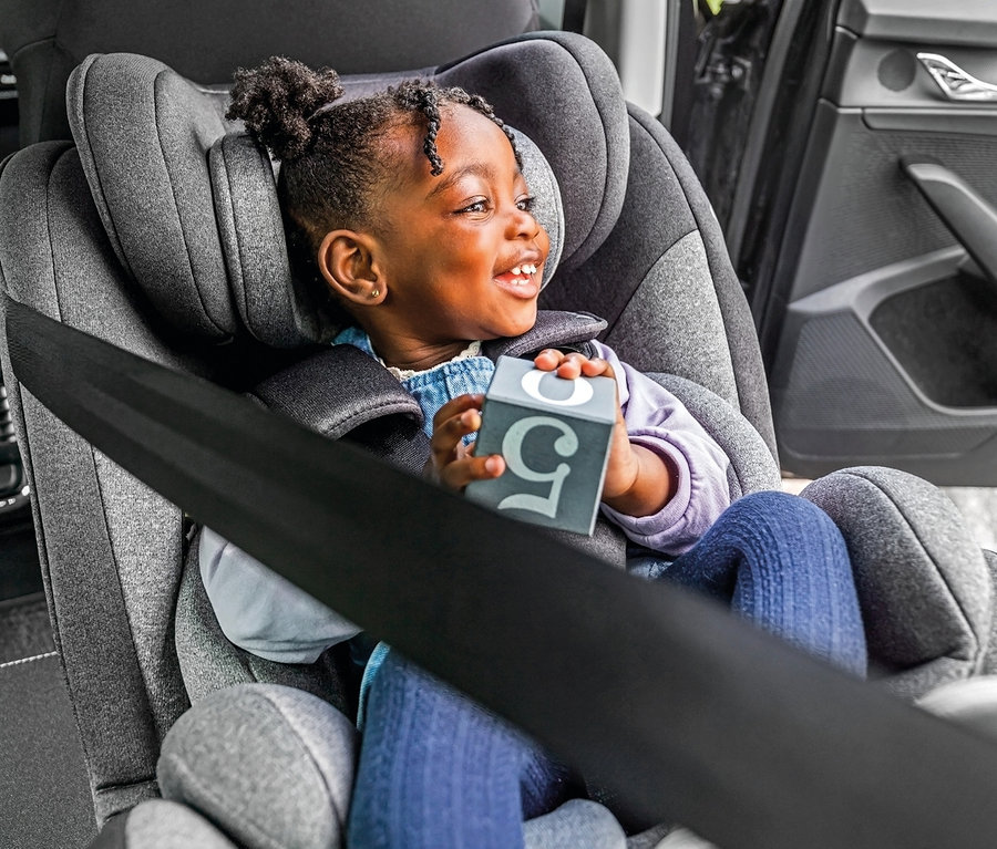 Mädchen sitzt im Osann Kindersitz »Swift360 S« und hält einen Würfel mit der Nummer fünf.