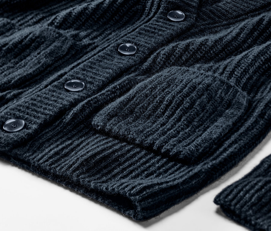 Detailansicht eines dunkelblauen, gerippten Grobstrick-Cardigans mit Knöpfen und Tasche.
