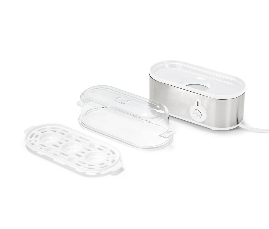 Ein Eierkocher-Set besteht aus einem silbernen Eierkocher, einem transparenten Deckel und einem weißen Eierhalter.